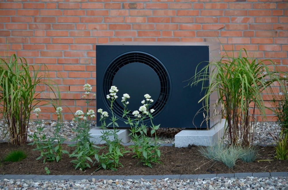 Buitenunit van een warmtepomp in tuin